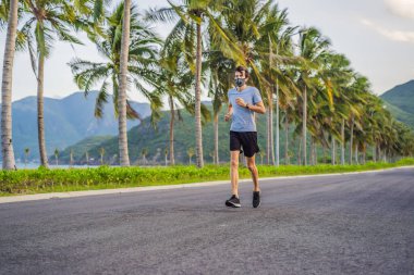 Tıbbi maske takan bir kaçakçı, Coronavirüs salgını Covid-19. Spor, karantinada aktif yaşam yüz maskesi korumalı cerrahi sterilizasyon. Corona Salgını 'nda atletizm pistinde açık hava koşusu