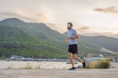Tıbbi maske takan bir kaçakçı, Coronavirüs salgını Covid-19. Spor, karantinada aktif yaşam yüz maskesi korumalı cerrahi sterilizasyon. Corona Salgını 'nda atletizm pistinde açık hava koşusu