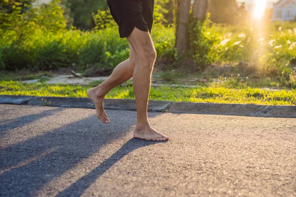 Un corredor de hombre se dedica a correr sobre el asfalto sin zapatos, sin zapatillas de deporte, para la salud — Foto de Stock