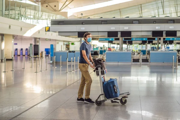 Maskierter Mann am leeren Flughafen beim Check-in in Coronavirus-Quarantäne-Isolation, Heimkehr, Flugausfall, weltweite Ausbreitung der Pandemie, Reisebeschränkungen und Grenzschließung — Stockfoto