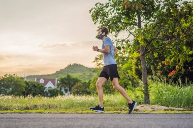 Tıbbi maske takan bir kaçakçı, Coronavirüs salgını Covid-19. Spor, karantinada aktif yaşam yüz maskesi korumalı cerrahi sterilizasyon. Corona Salgını 'nda atletizm pistinde açık hava koşusu