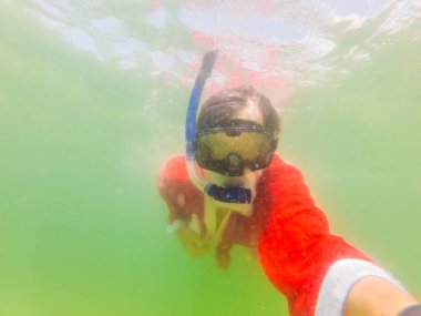 Noel Baba su altında şnorkelle yüzüyor. Noel ya da mutlu yıllar konsepti. Karantina kaldırıldıktan sonra tropiklerde Noel Coronovirus COVID 19 konsepti