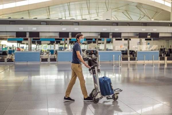 Ο άνθρωπος με μάσκα σε άδειο αεροδρόμιο κατά το check-in σε απομόνωση καραντίνας coronavirus, επιστροφή στο σπίτι, ακύρωση πτήσης, πανδημία μόλυνση σε όλο τον κόσμο εξάπλωση, ταξιδιωτικούς περιορισμούς και το κλείσιμο των συνόρων — Φωτογραφία Αρχείου