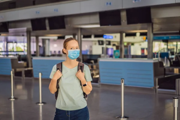 Женщина в маске в пустом аэропорту при регистрации в коронавирусной карантинной изоляции, возвращение домой, аннулирование рейсов, распространение пандемии по всему миру, ограничения на поездки и закрытие границ — стоковое фото