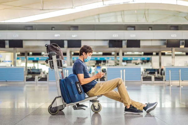 Maskierter Mann am leeren Flughafen beim Check-in in Coronavirus-Quarantäne-Isolation, Heimkehr, Flugausfall, weltweite Ausbreitung der Pandemie, Reisebeschränkungen und Grenzschließung — Stockfoto