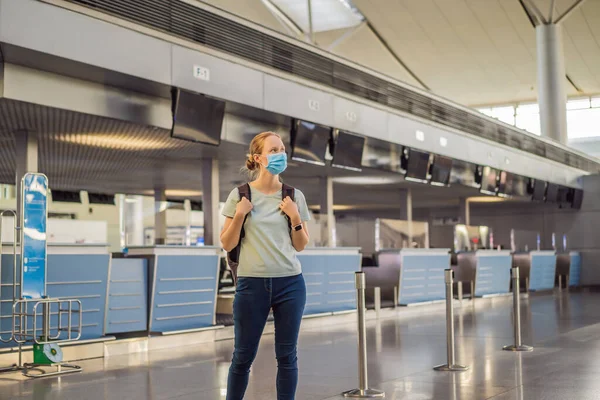 Maskierte Frau am leeren Flughafen beim Check-in in Coronavirus-Quarantäne-Isolation, Heimkehr, Flugausfall, weltweite Ausbreitung der Pandemie, Reisebeschränkungen und Grenzschließung — Stockfoto