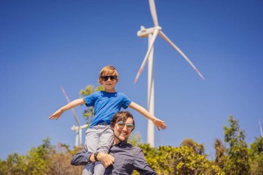 Alternatif enerji, rüzgar çiftliği ve ailenle mutlu zaman geçirmek. Oğlunu omuzlarında taşıyan mutlu baba tatilde ve doğaya kaçıyor. Baba oğlunu omuzlarında taşır ve kollarını sallar.