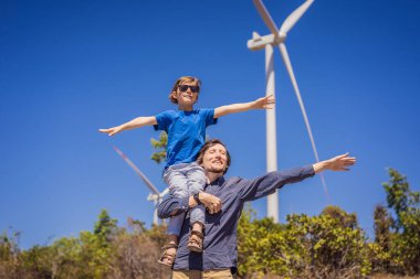 Alternatif enerji, rüzgar çiftliği ve ailenle mutlu zaman geçirmek. Oğlunu omuzlarında taşıyan mutlu baba tatilde ve doğaya kaçıyor. Baba oğlunu omuzlarında taşır ve kollarını sallar.