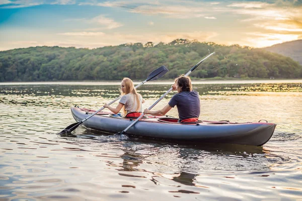 L'uomo e la donna nuotano sul kayak in mare sullo sfondo dell'isola. Concetto di kayaking.Concetto di kayak con famiglia di madre di padre in mare — Foto Stock