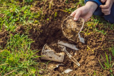 Çocuk geri dönüşüm çalıyor. Plastik tek kullanımlık tabakları ve ayrıştırılabilir tabakları gömüyor. Birkaç ay sonra, bulaşıkları kazıp çıkardı ve ayrıştırılabilir tabakların çözülmeye başladığını gördü.