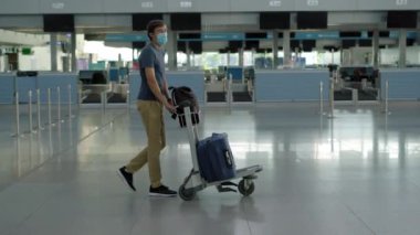 Koronavirüs karantinasında kontrol altında tutulan maskeli adam, eve dönüyor, uçuş iptali, dünya çapında yayılan salgın hastalık, seyahat kısıtlamaları ve sınır kapatma.