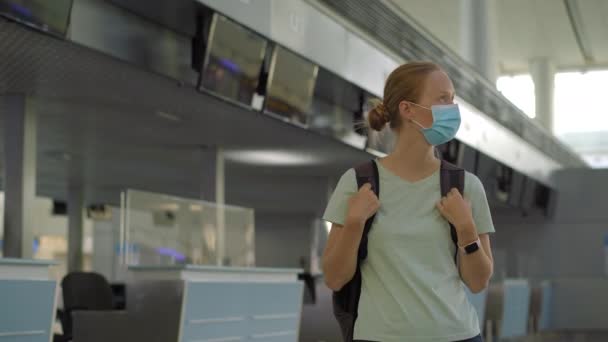 Жінка в масці в порожньому аеропорту під час перевірки ізоляції коронавірусу, повернення додому, скасування польоту, поширення пандемії у всьому світі, обмеження на поїздки та закриття кордону — стокове відео