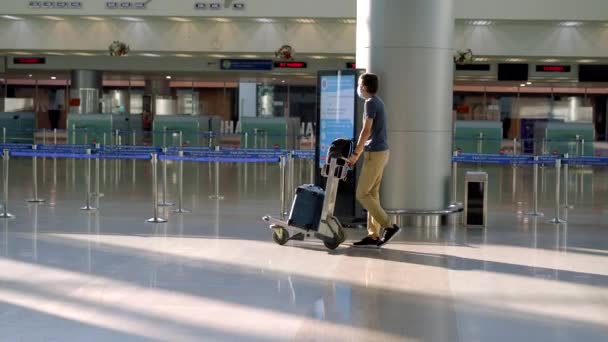 30.05.2021, Vietnam, Ho Chi Minh Stad: Man met masker op lege luchthaven bij het inchecken in quarantaine-isolatie van het coronavirus, thuiskomst, annulering van de vlucht, wereldwijde verspreiding van pandemische infectie, reizen — Stockvideo