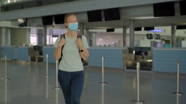 Mujer enmascarada en el aeropuerto vacío en el check in en aislamiento de cuarentena coronavirus, regresar a casa, cancelación de vuelos, infección pandémica en todo el mundo, restricciones de viaje y cierre de fronteras — Vídeos de Stock