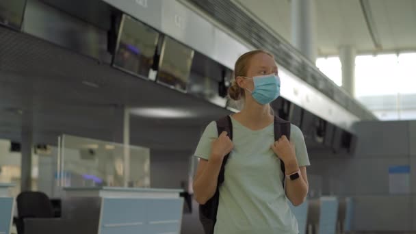 Kvinde i maske i tom lufthavn ved indtjekning i coronavirus karantæne isolation, vender hjem, aflysning af fly, pandemisk infektion verdensomspændende spredning, rejserestriktioner og grænsenedlukning – Stock-video