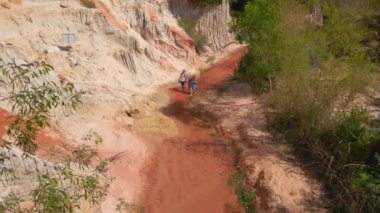 Havadan yavaş çekim. Bir aile, Güney Vietnam 'daki Mui Ne köyündeki çöl sınırında kırmızı kanyon ya da peri deresi boyunca yürür.