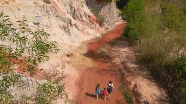 Lançamento em câmara lenta. Uma família caminha ao longo de um desfiladeiro vermelho ou fluxo de fadas na fronteira do deserto na aldeia de Mui Ne, no sul do Vietnã — Vídeo de Stock