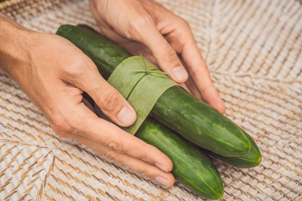 Concepto de envasado de productos ecológicos. Pepino envuelto en una hoja de plátano, como alternativa a una bolsa de plástico. Concepto de cero residuos. Envases alternativos —  Fotos de Stock