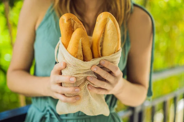 若い女性の手にパンと再利用可能な食料品袋。廃棄物ゼロショッピング。廃棄物ゼロコンセプト — ストック写真