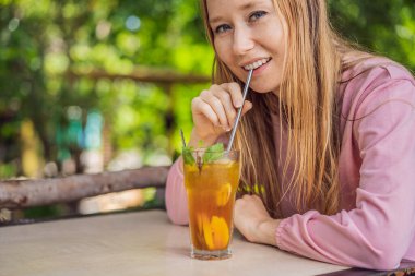 Yeniden kullanılabilir paslanmaz çelik pipet kullanarak meyve çayı içen çevre dostu bir kadın.