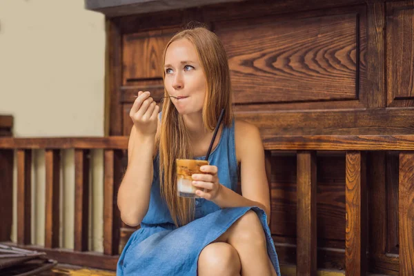 Счастливая красивая девушка сидит на лестнице в парке и пьет кофе со льдом — стоковое фото