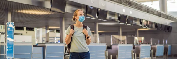BANNER, LONG FORMAT Frau mit Maske auf leerem Flughafen beim Check-in in Coronavirus-Quarantäne-Isolation, Heimkehr, Flugausfall, weltweite Ausbreitung der Pandemie, Reisebeschränkungen und — Stockfoto