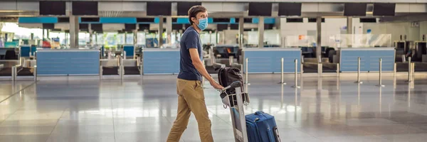 BANNER, LONG FORMAT Man in mask at empty airport at check in in coronavirus quarantine isolation, returning home, flight cancellation, pandemic infection worldwide spread, travel restrictions and