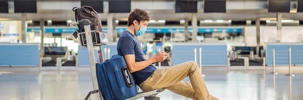 BANNER, LONG FORMAT Man in mask at empty airport at check in in coronavirus quarantine isolation, returning home, flight cancellation, pandemic infection worldwide spread, travel restrictions and