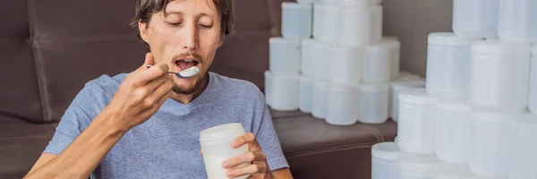 BANNER, LONG FORMAT The man eats yogurt and is surrounded by many jars of yoghurt that he uses in a year. A huge amount of plastic food jars. Excessive consumption of plastic. Reduce, reuse, recycle — Stock Photo, Image