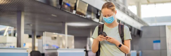 BANNER, LONG FORMAT Woman in mask at empty airport at check in in in coronavirus quarantine isolation, returning home, flight cancellation, pandemic infection worldwide spread, travel restrictions and — стоковое фото