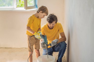 Oğluyla evde tamirat yapan bir adam, çocuklara ellerinde bir spatulayla duvarları alçılamayı öğretiyor.