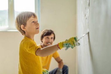 Oğluyla evde tamirat yapan bir adam, çocuklara ellerinde bir spatulayla duvarları alçılamayı öğretiyor.