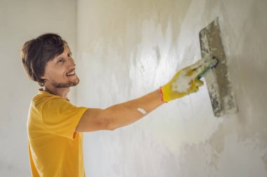 Sıvacı ev iyileştirme ustası macun bıçağıyla apartman duvarını doldurmaya çalışıyor.