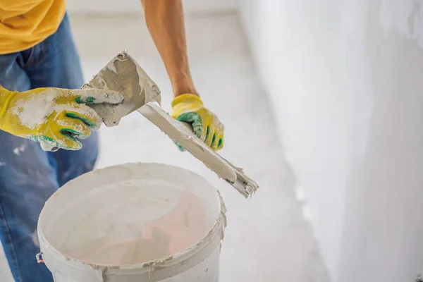 Gesso casa melhoria trabalhador manual com faca de vidraceiro trabalhando no recheio de parede do apartamento — Fotografia de Stock
