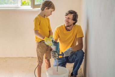 Oğluyla evde tamirat yapan bir adam, çocuklara ellerinde bir spatulayla duvarları alçılamayı öğretiyor.