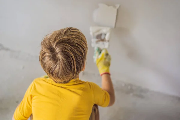 Çocuk evde tamirat yapıyor, çocuklara ellerinde bir spatulayla duvarları alçılamayı öğretiyor. — Stok fotoğraf