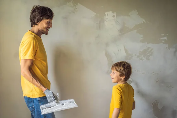 Az ember a fiával otthon javít, gyerekeket tanít arra, hogy ragasszák fel a falakat egy spatulával a kezében. — Stock Fotó