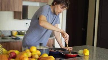 Genç bir adam mutfakta yemek pişiriyor, lezzetli bir ev yemeği hazırlamaya odaklanıyor. Sıcacık bir ortamda ev yapımı, yaratıcılık ve aşçılık keyfi.