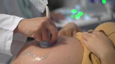 Klinikteki ultrason taraması sırasında karnının yakın çekimi. Doğum öncesi bakım ve annelik kavramı.