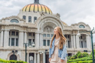 Mexico City 'de Palacio de Bellas Artes' in önünde duran kadın turist, Meksika kültürünün, mimarisinin ve simgesel seyahat simgelerinin güzelliklerini yakalıyor..