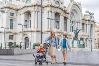 İki oğlu ile birlikte Mexico City 'deki Palacio de Bellas Artes' in önünde aile seyahatinin, mimarinin ve kültürel mirasının tadını çıkaran bir anne turist. Aile seyahati ve bağlanma kavramı.
