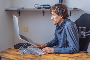 Evinde çalışan bir adam, modern ve parlak bir çalışma alanında dizüstü bilgisayarına odaklanmıştı. Uzak çalışma, üretkenlik, serbest yaşam tarzı ve çağdaş küresel iş yeri kavramı.