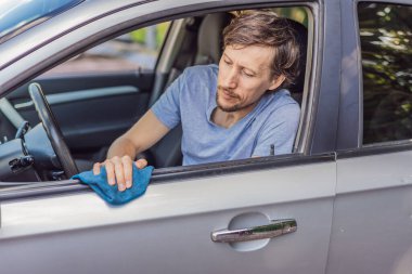 Adam arabasının içini temizliyor, yüzeyi siliyor ve aracı düzenliyor, temizlik, bakım ve günlük rutin işler..