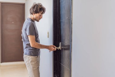 Adam, evin güvenliğini ve güvenliğini sağlamak için kapıyı anahtarla kilitliyor. Kişisel güvenlik kavramı, ev hayatı, sorumluluk ve modern yaşam tarzı.