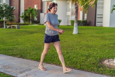 Yaşlı bir kadın çimenli bir çimenlikte egzersiz yapıyor, aktif, güçlü ve dışarıda sağlıklı kalıyor. Aktif yaşlanma, sağlık, kondisyon, hareketlilik, pozitif yaşam tarzı ve sağlıklı yaşlı yaşam kavramı.