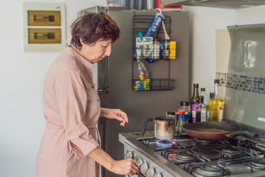 Mutfakta yemek pişiren yaşlı bir kadın, özenle ve neşeyle ev yemeği hazırlıyor. Sağlıklı yaşlanma, bağımsızlık, ev hayatı, aşçılık rutini ve evdeki aktif yaşlı yaşam tarzı kavramı.