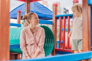 Bir anne, küçük oğluyla açık havada oyun oynarken keyifli aile zamanlarının ve ebeveynlik anlarının tadını çıkarıyor. Çocukluk eğlencesi, bağlanma, kahkaha ve kaygısız ilk yıllar konsepti..
