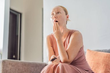 Kadın evde dinleniyor ve televizyonda film seyrediyor. Huzurlu bir akşam atmosferinin tadını çıkarıyor. Konforlu yaşam tarzı, rahatlık ve eğlence konsepti, konforu, sakinliği ve modern evi temsil ediyor.