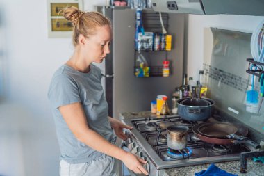 Kadın, parlak bir ev mutfağında kahvaltı hazırlıyor, sakin bir sabah rutininin tadını çıkarıyor ve güne sıcak bir başlangıç yapıyor. Sağlıklı yaşam tarzı, ev yemekleri ve rahat ev hayatı.
