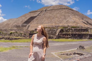 Meksika 'da Teotihuacan piramitlerinin önünde duran kadın turist gezinin, maceranın ve kültürel mirasın tadını çıkarıyor. Seyahat, turizm ve keşif konsepti.